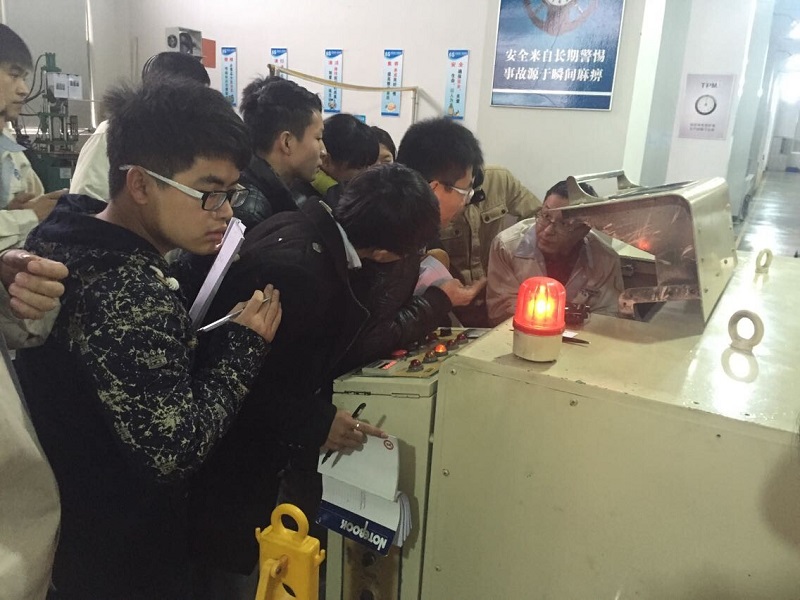 實(shí)習(xí)大學(xué)生聚精會(huì)神的聽周師傅講解機(jī)器操作方法